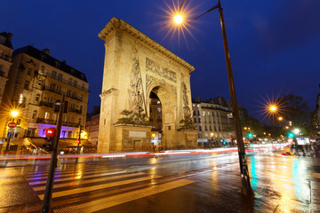 Porte Saint-Denis at rainy night . It is a Parisian monument located in the 10th arrondissement of...