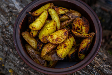 Homemade crispy potatoes on a frying pan on the fire outside. Picnic in nature with cooking.