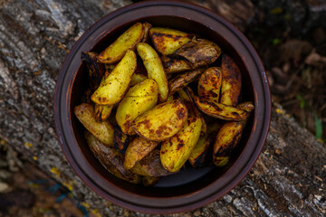Homemade crispy potatoes on a frying pan on the fire outside. Picnic in nature with cooking.