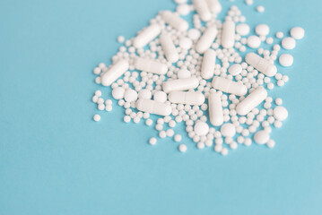White pills on a blue background. Capsules and round pills close-up. Healthcare and medicine.