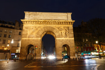 Fototapeta na wymiar Paris, the porte Saint-Martin, beautiful ancient gate near the Grands Boulevards at rainy night.