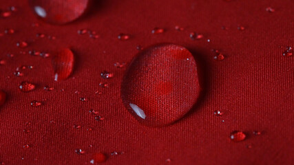 Waterproof textile cloth concept. Rain, water drops are splashing on coat but waterproof is saving...