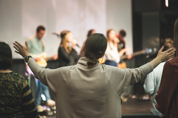 Hands in the air of a woman who praise God at church service - obrazy, fototapety, plakaty