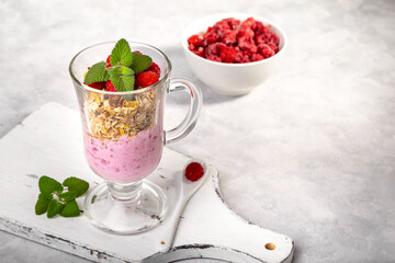 Raspberry smoothie and homemade granola in a transparent glass. Healthy breakfast or snack. Copy space