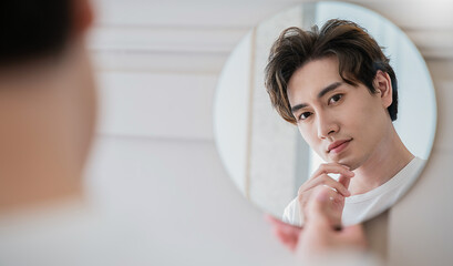 Closeup portrait of handsome beautiful asian boy with mirror makeup routine with copy space. Beauty...