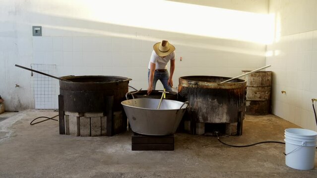 Muchacho se&ntilde;or trabajador preparando haciendo y cocinando rico y delicioso platillo t&iacute;pico carnitas comida carne de cerdo puerco en manteca aceite