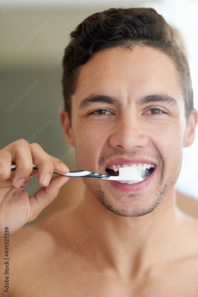 Sticker The germs dont stand a chance. Shot of a handsome young man brushing his teeth at home.