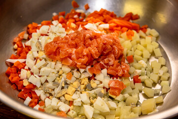The chef prepares Olivier salad, mixes all the ingredients and adds mayonnaise
