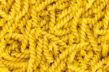 Raw pasta fusilli. spiral shape pasta, yellow background