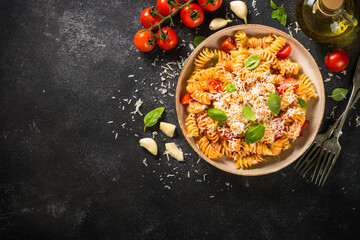 Italian pasta alla arrabiata with basil and parmesan on dark table. Top view image with space for design.