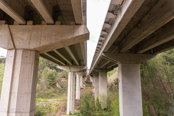 Underside of a bridge, with a view of the large cement piers.