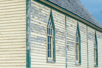 The exterior wall of a religious building with pale yellow colored narrow horizontal clapboard...