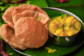 south indian famous breakfast poori or puri with potato curry served in a plate with banana leaf closeup with selective focus and blur - obrazy, fototapety, plakaty
