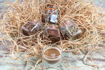 different types of coffee beans in small jars and a glass of coffee