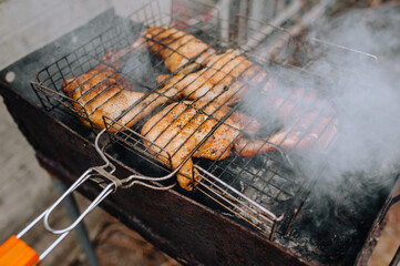 Chicken thighs are fried on the grill in a barbecue. Picnic in nature.