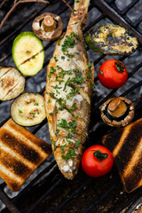 Freshly cooked fish with vegetables and bread in nature. A successful fishing in nature with a grilled fish.