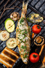 Freshly cooked fish with vegetables and bread in nature. A successful fishing in nature with a grilled fish.