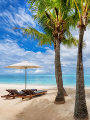 Beach umbrellas, Palm trees and chairs in tropical sunny beach resort in Mauritius island.