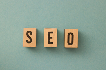 SEO - Search Engine Optimization letters made out of wood on the turquoise background