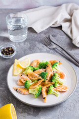 Fried broccoli and shrimp on a plate on the table. Vertical view