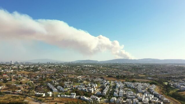 Incendio en montaña campo cerro cerca de ciudad casas viviendas gran cantidad de humo saliendo por el fuego caliente 