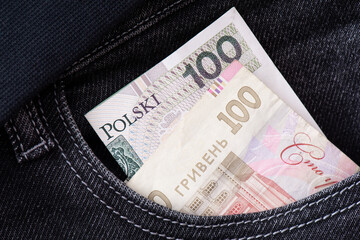 Obraz premium Ukrainian hryvnia and Polish zloty protrude from the pocket of jeans close-up. Banknotes of neighboring countries. The concept of unity and mutual assistance of Ukraine and Poland. Money exchange.