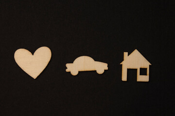 Wooden symbols, blocks on the black background heart car and house