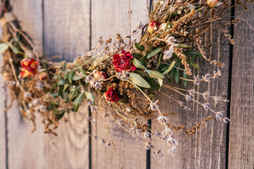 Close up photo, part of twisted crafting, arvensis creative dry herbal wreath from twigs of wild flowers, cereal and grass. Traditional festive ethnic decoration on entrance door. Low angle view - Powered by Adobe