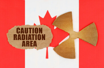 On the flag of Canada, the symbol of radioactivity and torn cardboard with the inscription - caution radiation area