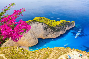 Famous Shipwreck Navagio Beach with pink Bougainvillea flower on Zakynthos island, Greece. Greece iconic vacation picture.
