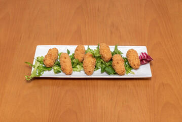 Delicious and typical Spanish croquettes of serrano ham on a bed of lettuce served in a Spanish tapas restaurant