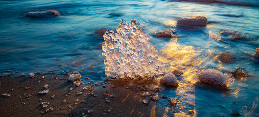 Close-up of piece of ice on snowy beach of Baltic sea at winter. - obrazy, fototapety, plakaty