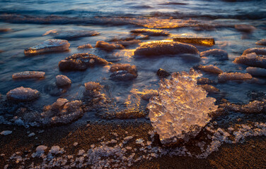Close-up of piece of ice on snowy beach of Baltic sea at winter. Long exposure. - obrazy, fototapety, plakaty