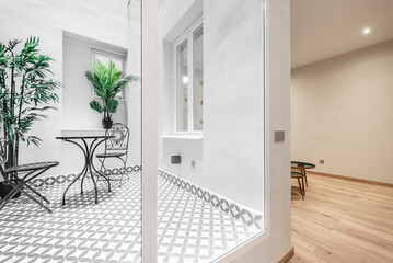 Interior of closed white aluminum and glass terrace with hydraulic stoneware floor, metal tables...