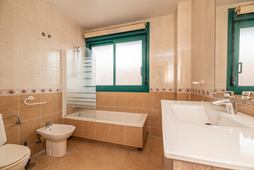 Fototapeta na wymiar Bathroom with a frameless mirror, one-piece white porcelain sink, walk-in shower over tub, and green aluminum window