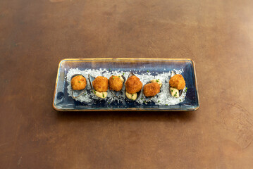 Delicious prawn croquettes served marine style on mussel shells, coarse salt and a blue plate