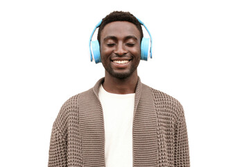 Portrait of happy smiling african man listening to music in wireless headphones wearing brown knitted cardigan isolated on white background