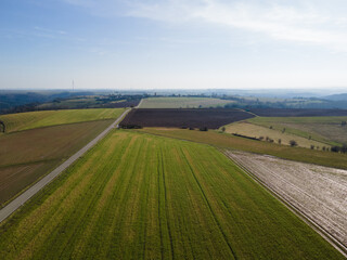 Aerial view of agricultural fields with a single lane road in the countryside on a sunny spring day