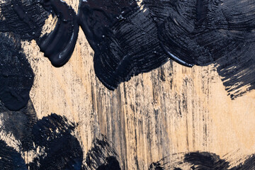 detalle de mancha de pintura negra sobre madera con textura áspera color claro