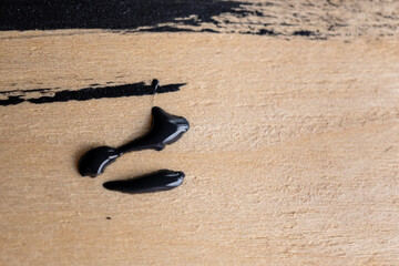 Fototapeta na wymiar detalle de mancha de pintura negra sobre madera con textura áspera color claro