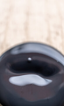 detalle de plasta de pintura negra acr&iacute;lica con poca profundidad de campo, sobre madera de pino