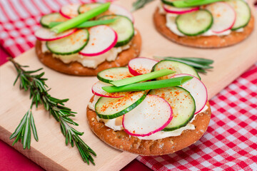 Light Breakfast or Diet Eating - Crispy Cracker Sandwich with Cream Cheese, Fresh Cucumber, Green Onions and Radish on Wooden Cooking Board on Magenta Background