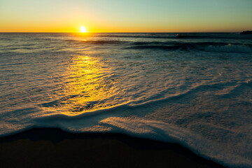 Amazing sunset on the Atlantic coast with foamy surf.