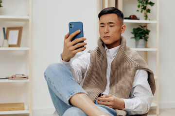 handsome man sitting in a chair in a room with phone on his lap