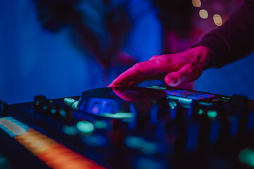 DJ Hands creating and regulating music on dj console mixer in concert nightclub