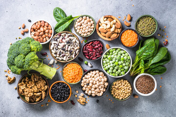 Vegan protein source. Legumes, beans, lentils, nuts, broccoli, spinach and seeds. Top view on gray stone table. Healthy vegetarian food.