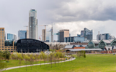 Panoramic cityscape of Brussels city center and economic district with skyscrapers in spring on a sunny day with a dramatic sky and a green park in the foreground