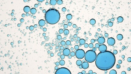Blue different sized drops of oil floating in clear fluid on white background | Macro shot of emolient ingredients for its commercial