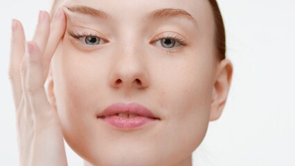 Big close-up shot of young European woman looks at camera stretching her skin on white background |...