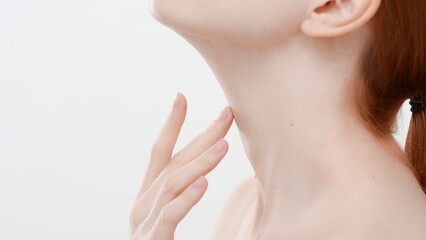 Extreme close-up of woman touches her neck standing sideways and looking up on white background | Nourishing cream commercial